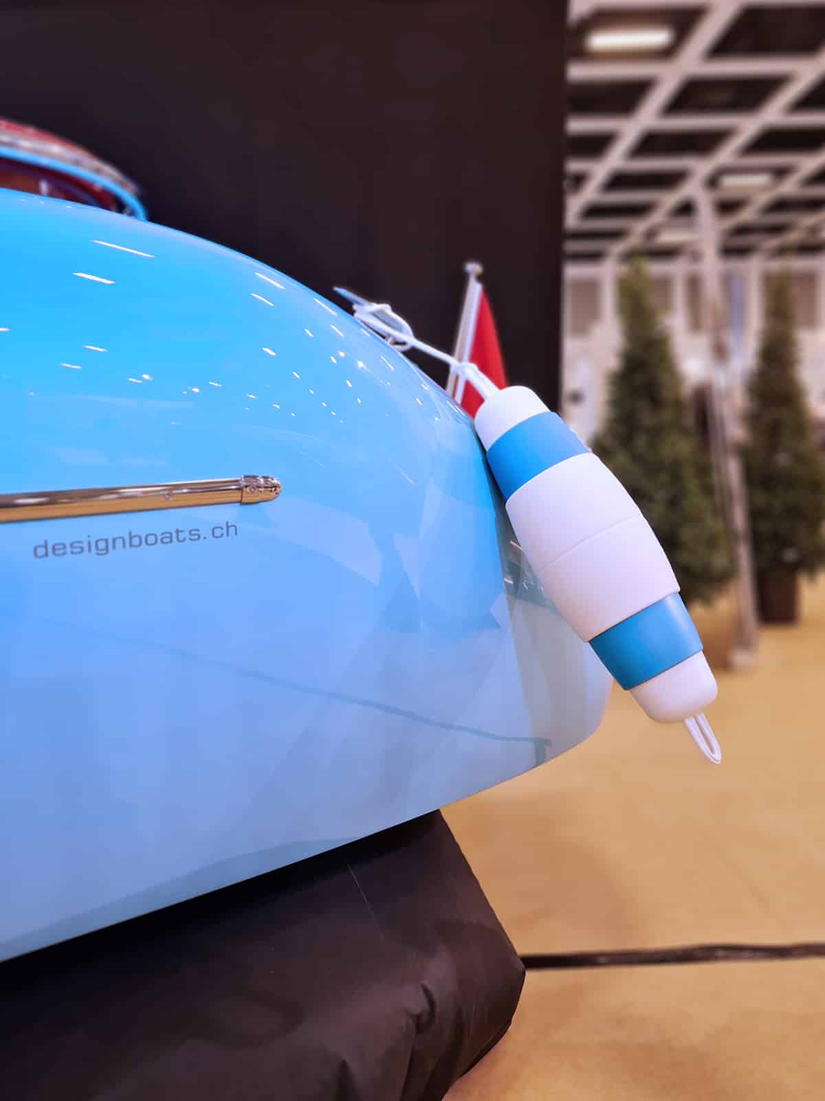 Blue boat with a white and blue float attached, indoors.