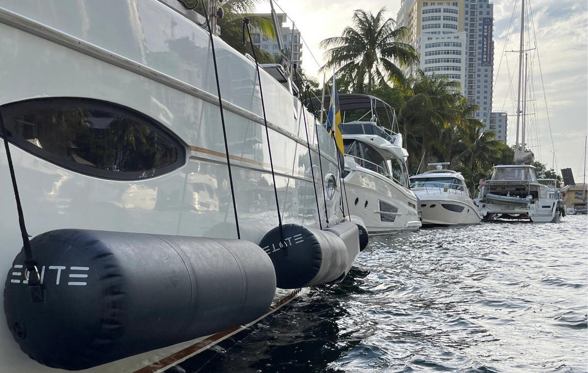 ELITE Boss cylindrical fenders along a motor yacht in a palm-lined marina.