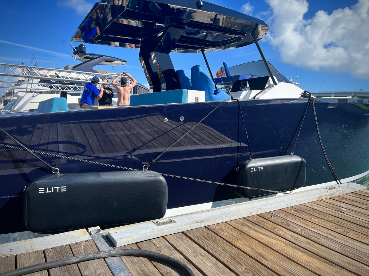 ELITE Sentinel flat fenders on a dark blue Tesoro motorboat beside a wooden dock.
